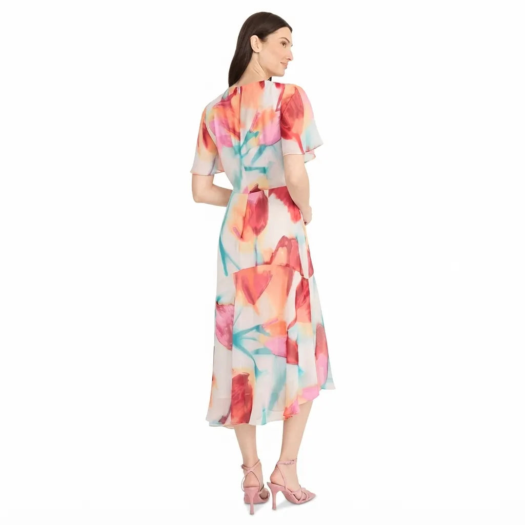 A woman modeling a short-sleeved midi dress with a colorful abstract watercolor floral print, shown from the back against a plain white background.