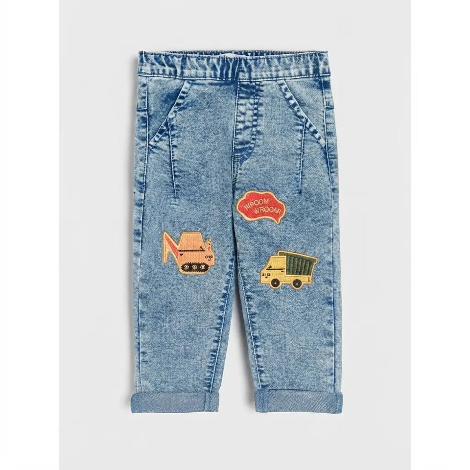 Light blue denim toddler pants with rolled cuffs and embroidered construction-themed patches, shown flat against a light gray background.