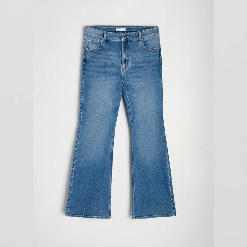 A pair of medium-wash blue denim jeans with a flared bootcut silhouette, laid flat against a light gray background.