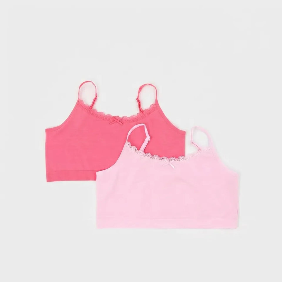 Two camisole-style crop tops in pink, one darker pink and one lighter pastel pink, laid flat on a light gray background. Both have thin straps, scalloped lace trim at the neckline, and a small bow detail at the center front.