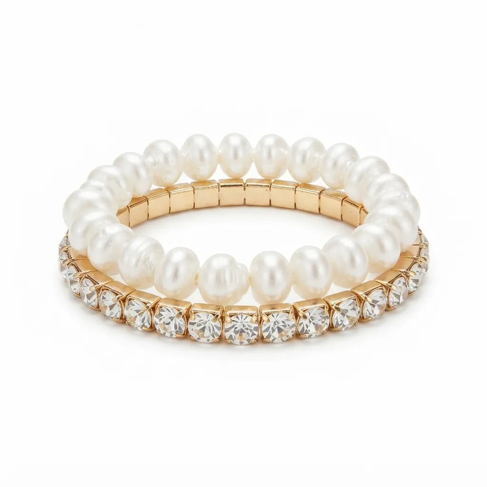 A stack of three stretch bracelets on a white background. The top bracelet is made of white pearls on a gold-tone band.