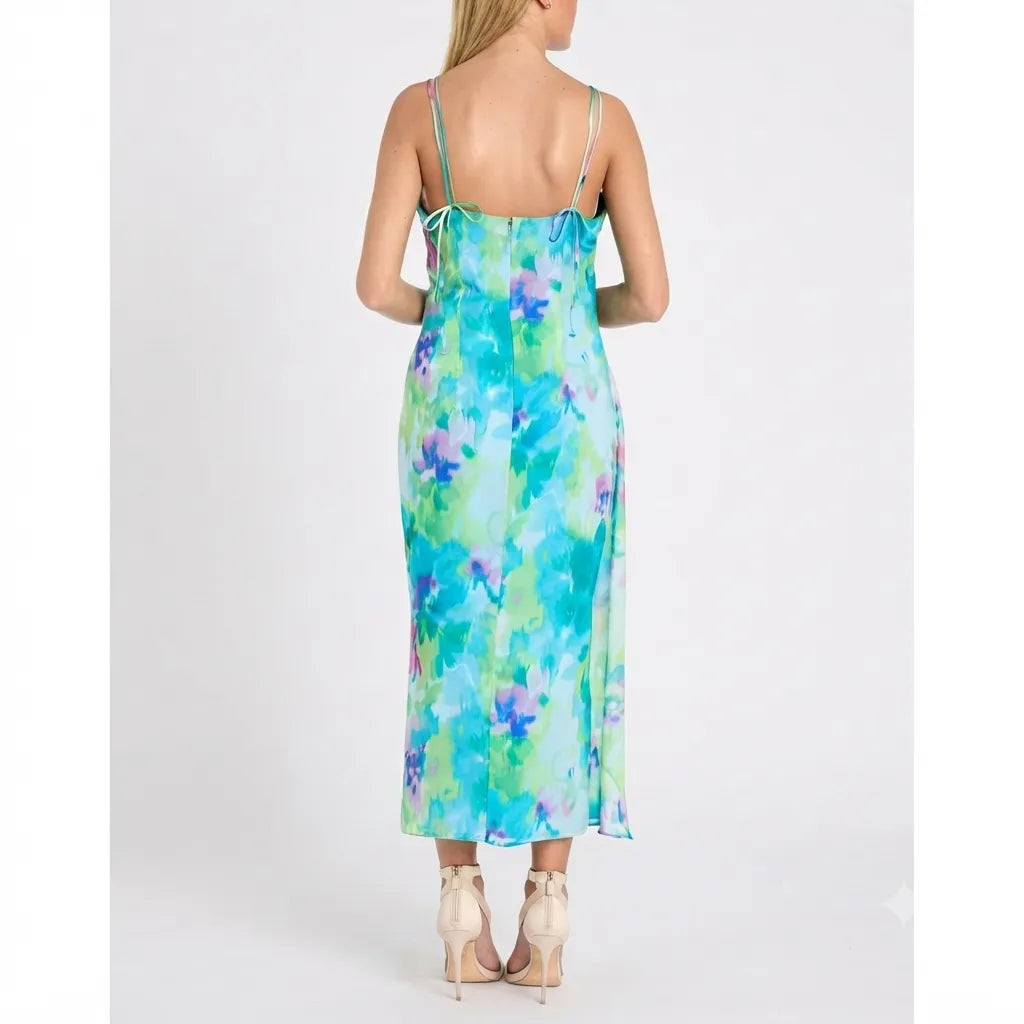 A woman shown from the back wearing a sleeveless midi slip dress with a blue, green, and purple watercolor floral print, paired with beige high heels, against a plain white studio background.
