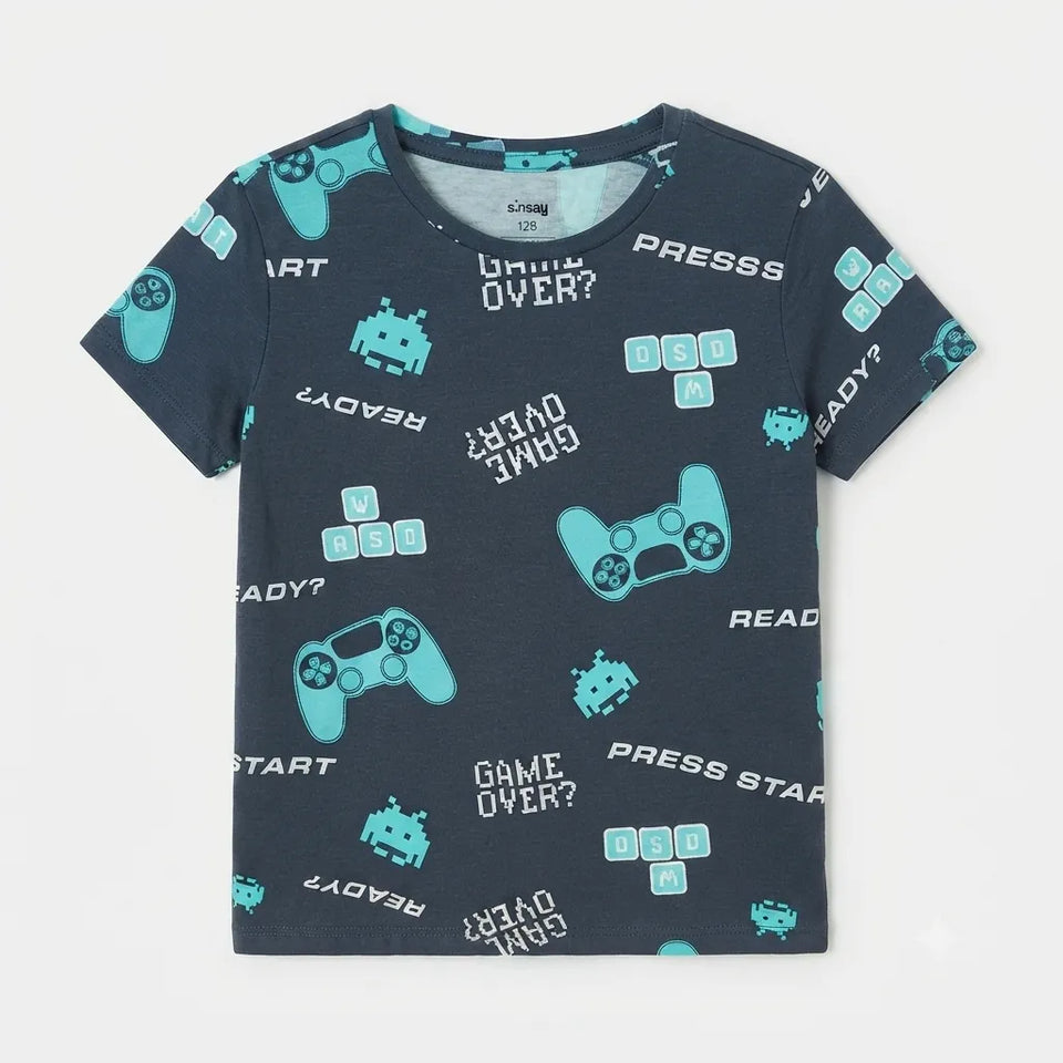 A navy blue short-sleeve t-shirt with a light blue and white video game theme print, featuring retro arcade characters, game controllers, and text like 'GAME OVER?' and 'PRESS START'.