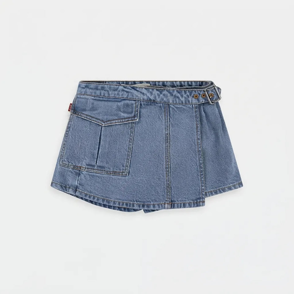 A light blue denim mini skirt with a unique asymmetrical front design, featuring a large front pocket, decorative stitching, and a buttoned waistband, shown against a plain white background.