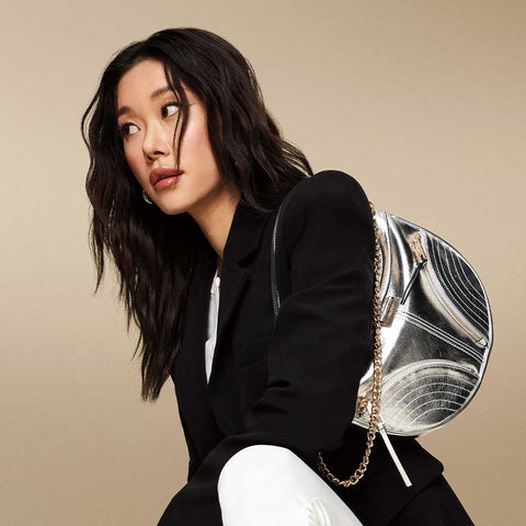 Woman holding a silver handbag against a beige background