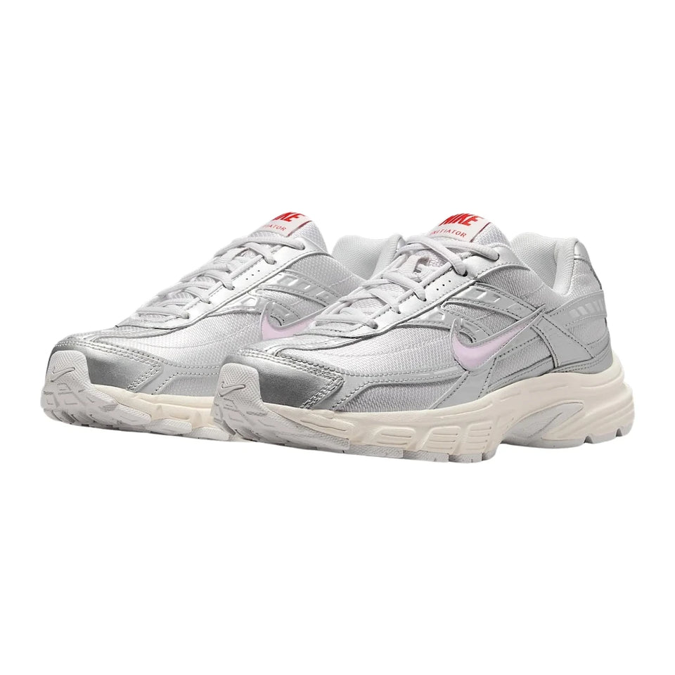 A pair of Nike Air Max 90 sneakers in metallic silver with light pink Swooshes and red tongue labels, set against a plain white background.