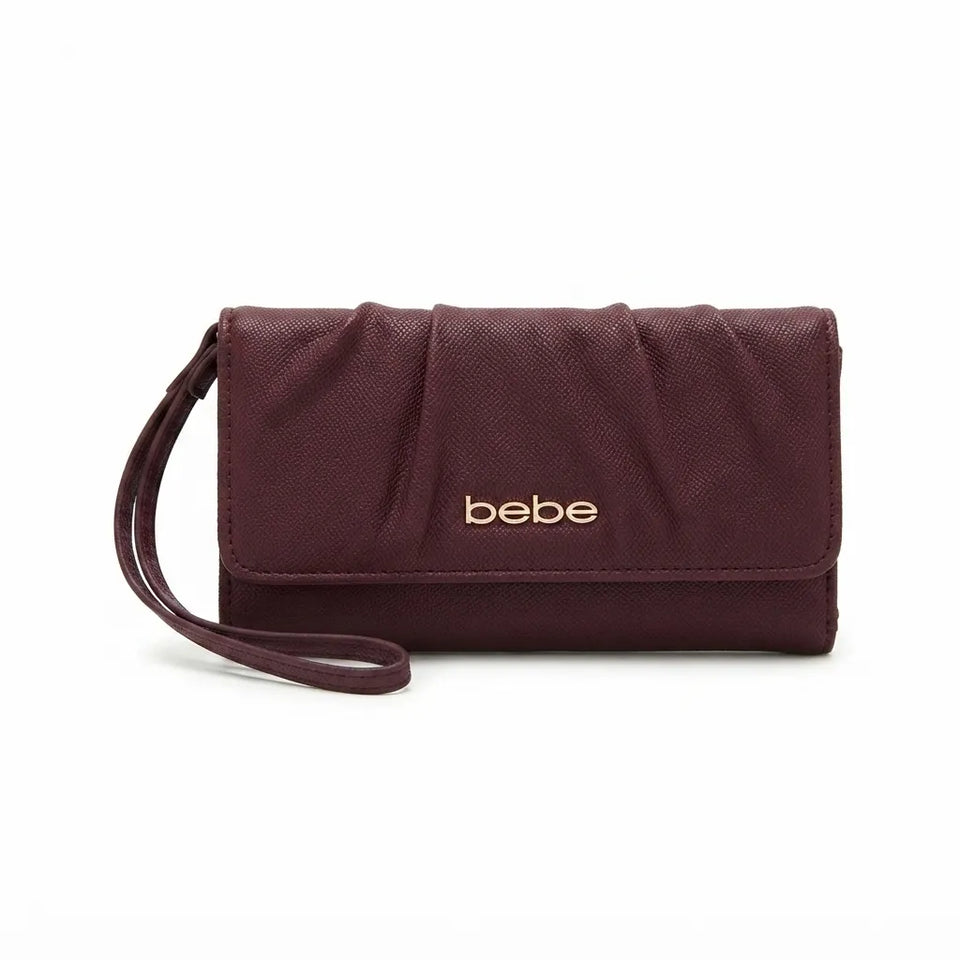 A burgundy textured faux-leather clutch wallet with a wristlet strap and gold-tone 'bebe' logo on the front, shown on a plain white background.