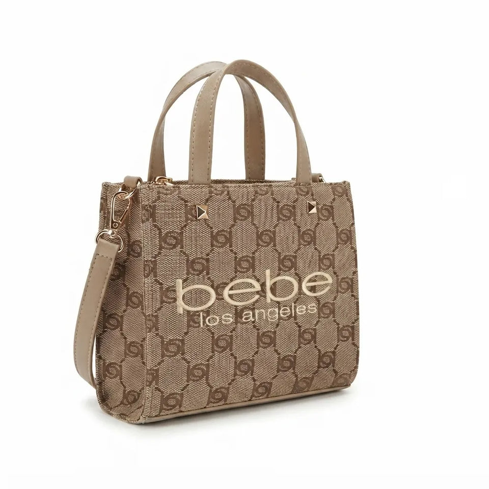 A beige and brown patterned tote bag with double top handles, a detachable shoulder strap, and gold-tone hardware. The front features the text 'bebe los angeles' in gold lettering, set against a clean white background.