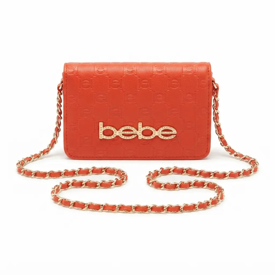 A vibrant orange-red crossbody bag with an embossed monogram pattern, a gold-tone 'bebe' logo on the front, and a matching chain strap, shown against a plain white background.