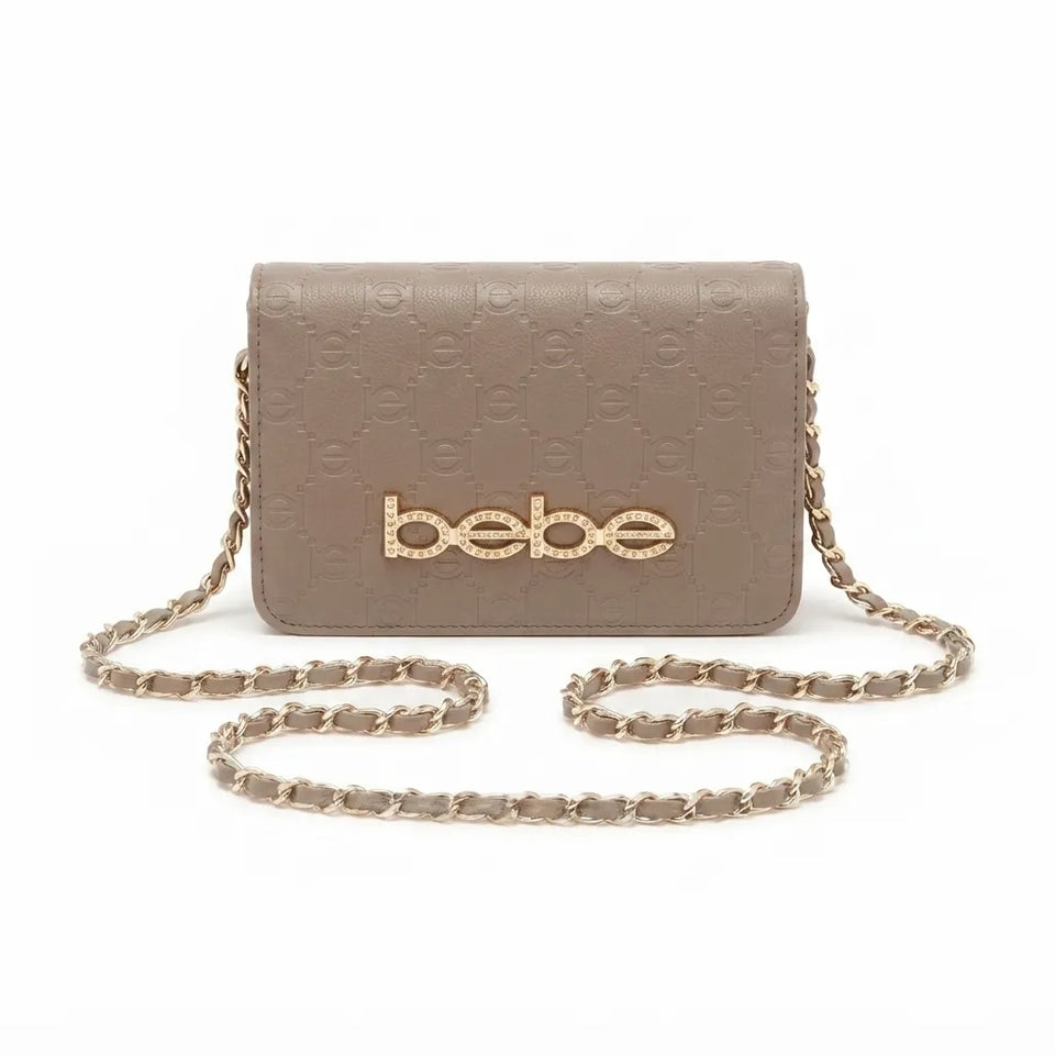 A taupe leather crossbody bag with an embossed monogram pattern, a gold-tone 'bebe' logo on the front, and a matching taupe and gold chain strap, shown against a plain white background.
