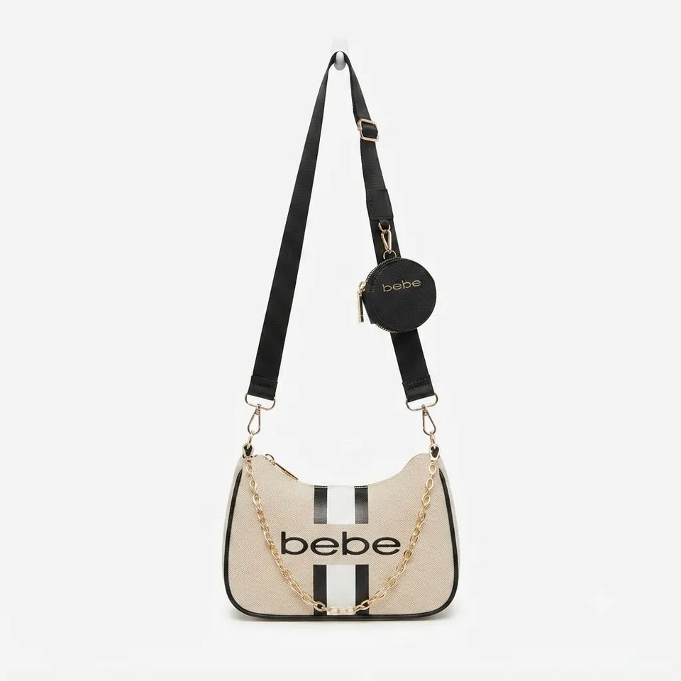 Bebe brand shoulder bag in beige textured canvas with black leather trim, black vertical stripes, a black adjustable shoulder strap, a gold chain detail, and a small black circular coin pouch with the brand name.