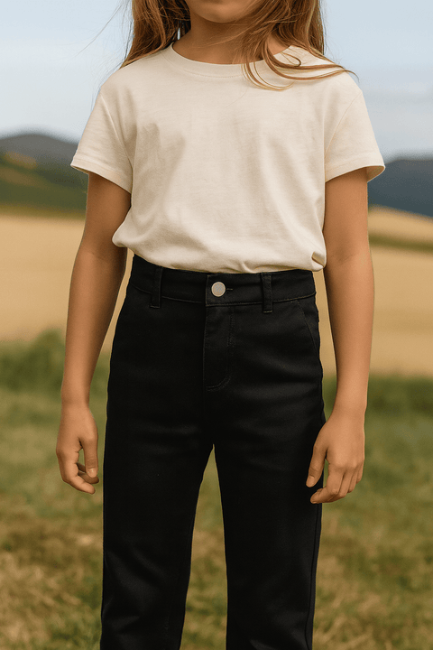 Person wearing a white t-shirt and black pants standing in a field with mountains in the background