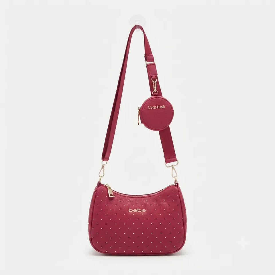 A burgundy studded crossbody bag with a matching round coin purse and adjustable shoulder strap, displayed on a light gray background.