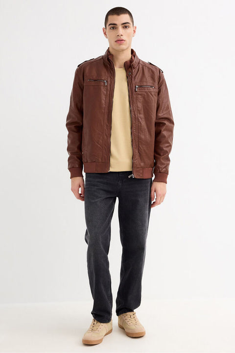 Man wearing a brown leather jacket, beige shirt, black pants, and tan shoes on a white background