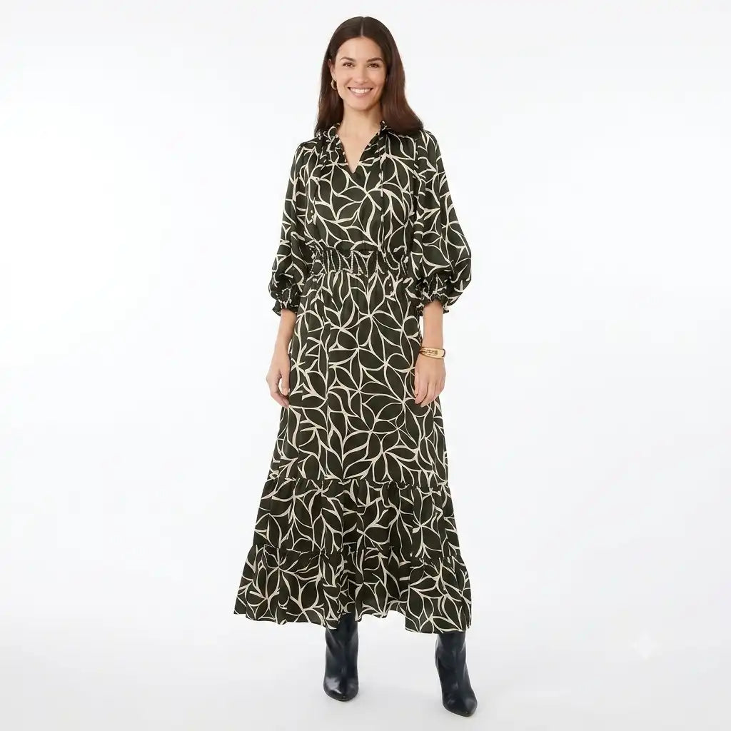 A woman modeling a long-sleeve midi dress with a black base and a white leaf pattern, paired with black ankle boots, against a plain white studio background.