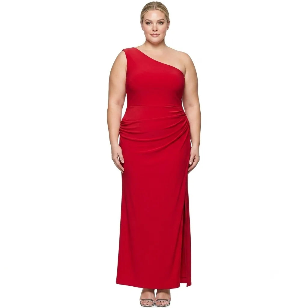 A plus-size model wearing a vibrant red one-shoulder maxi dress with a draped waist and side slit, standing against a plain white background.