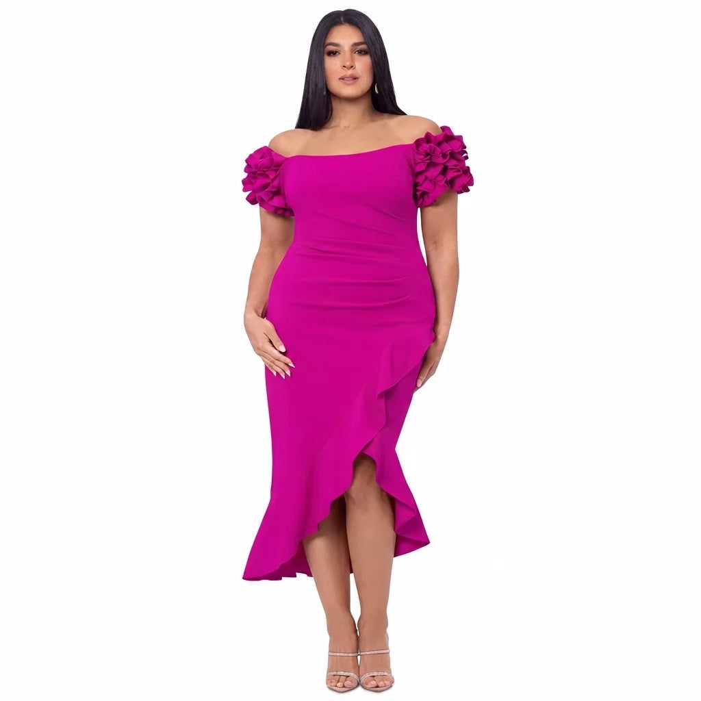 A woman modeling a bright fuchsia off-the-shoulder midi dress with ruffled cap sleeves and a high-low ruffled hem, paired with clear high-heeled sandals against a plain white background.