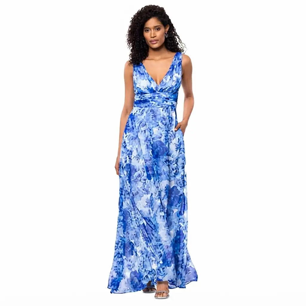 A woman modeling a sleeveless, V-neck maxi dress with a blue and white floral watercolor pattern, set against a plain white background.