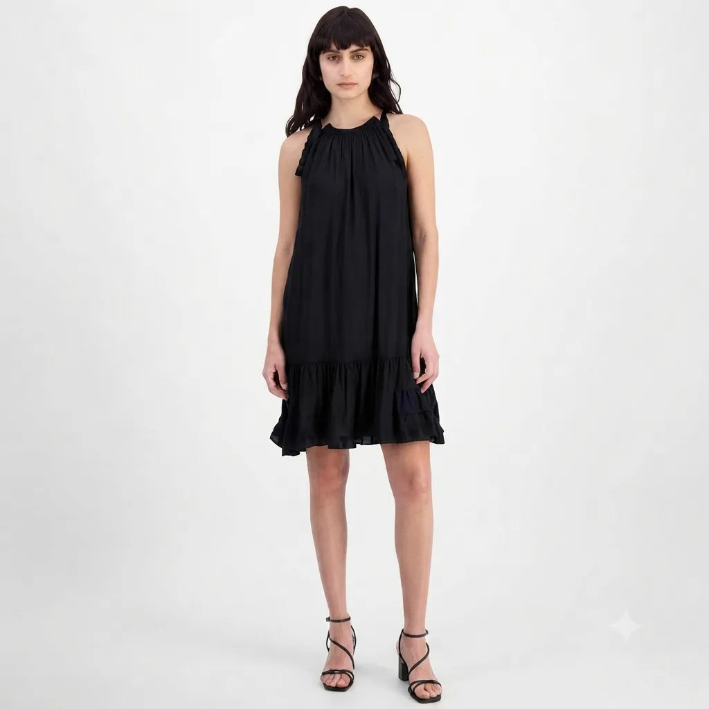 A woman modeling a sleeveless black halter-neck dress with ruffled trim at the neckline and a ruffled hem, paired with black strappy high-heeled sandals against a plain light gray studio background.