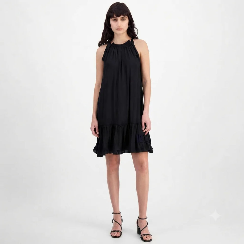 A woman modeling a sleeveless black halter-neck dress with ruffled trim at the neckline and a ruffled hem, paired with black strappy high-heeled sandals against a plain light gray studio background.