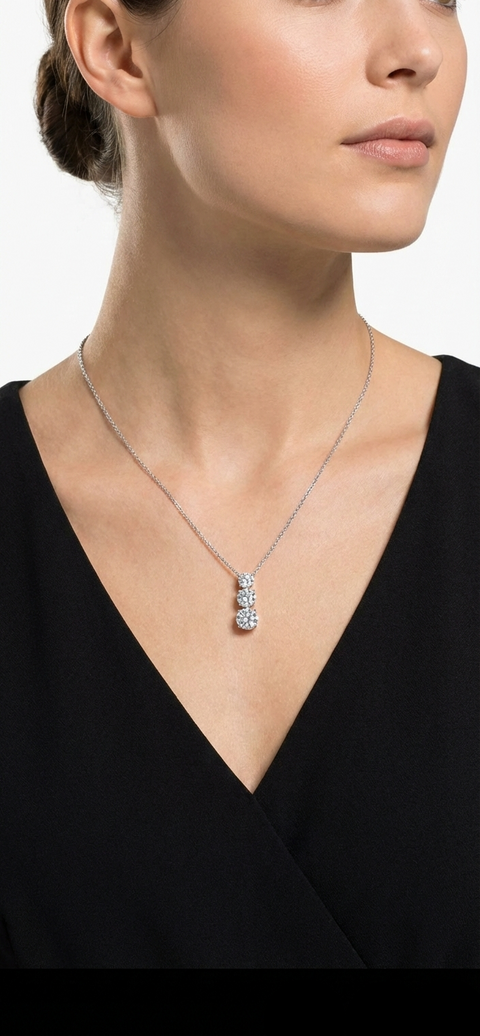 Woman wearing a black top with a silver necklace featuring a pendant.