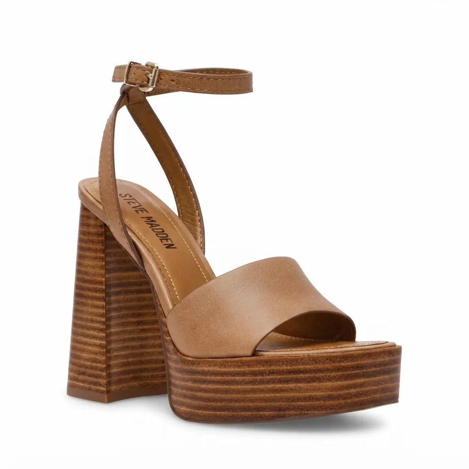 A Steve Madden platform sandal in tan leather with a brown wood-grain stacked heel and platform, featuring an ankle strap with a gold buckle.