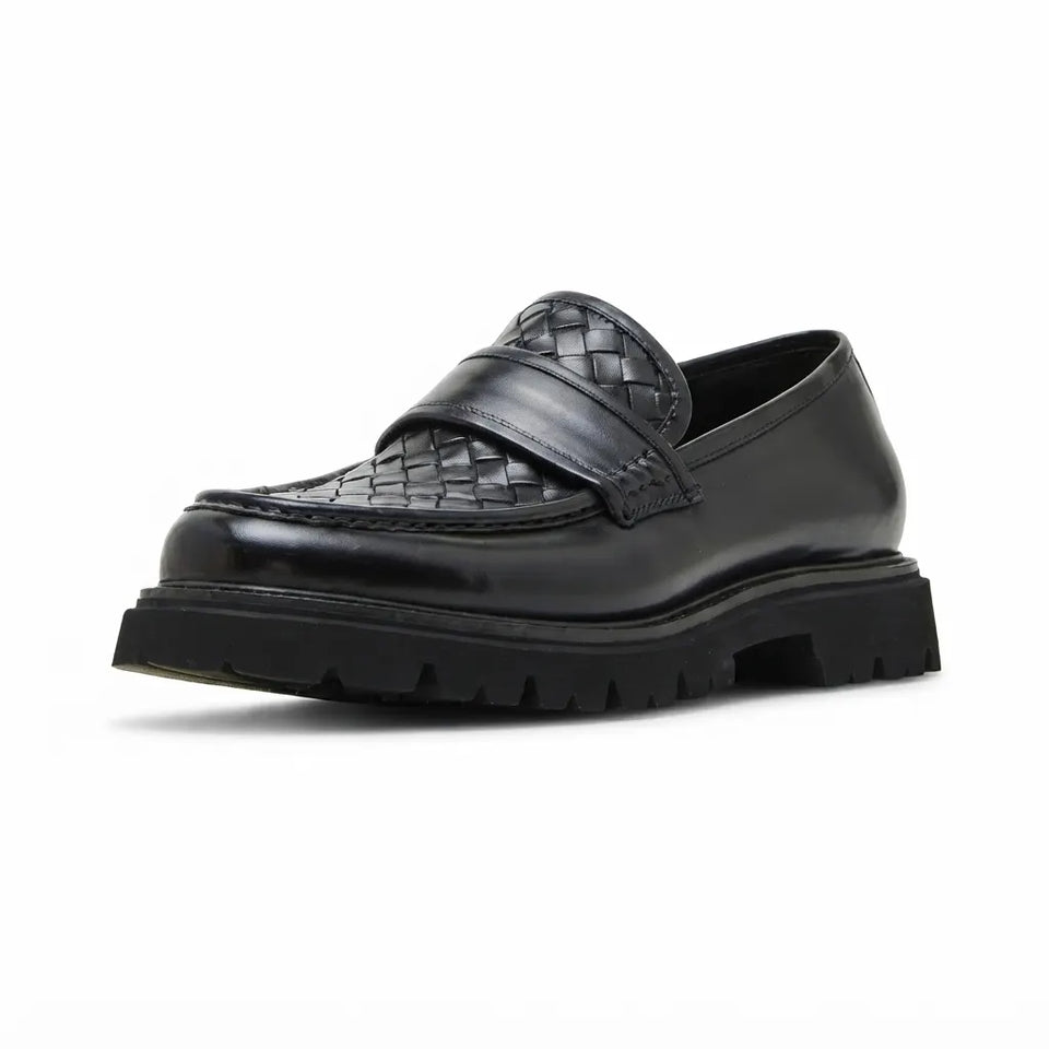 A single black leather loafer with a thick lug sole, featuring a smooth leather upper and a woven braided strap detail across the vamp, shown on a plain white background.