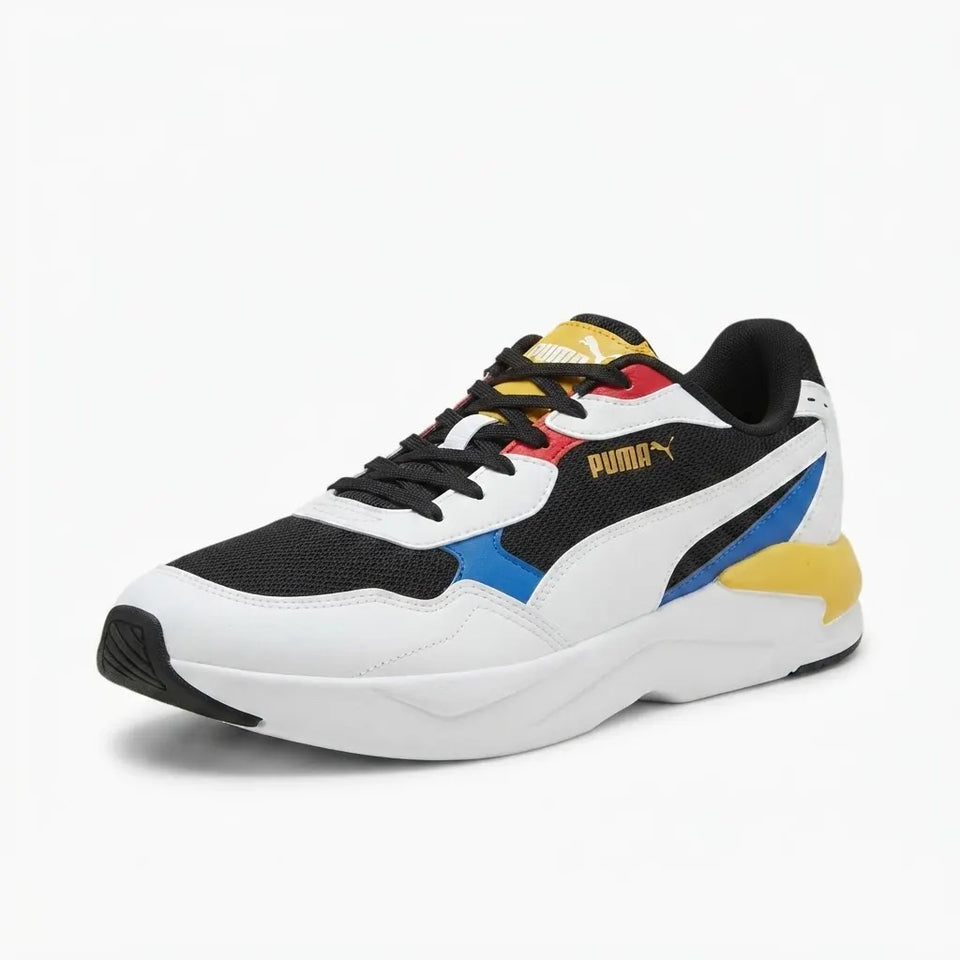 A Puma sneaker in white, black, blue, red, and yellow, shown from a three-quarters angle on a light gray background.