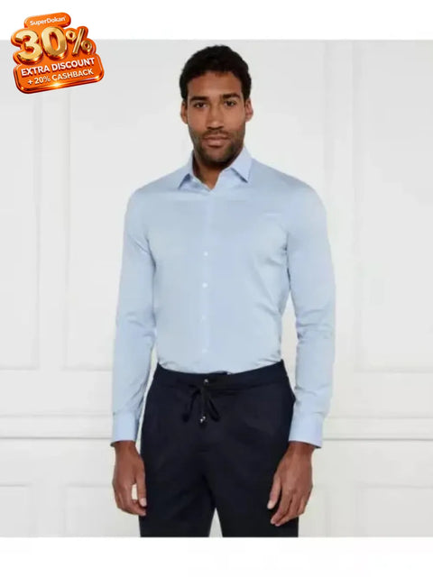 Man wearing a light blue dress shirt and dark pants against a white background