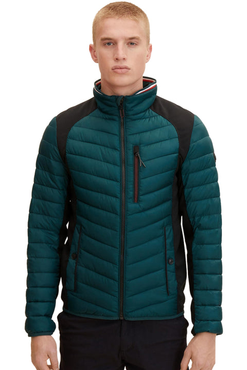 Man wearing a teal puffer jacket with a black backpack on a white background