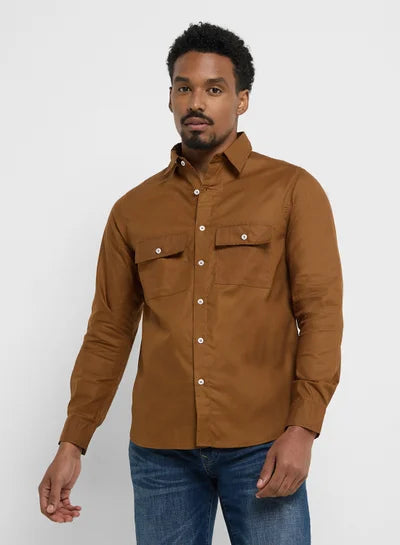 Man wearing a brown shirt with two front pockets on a white background