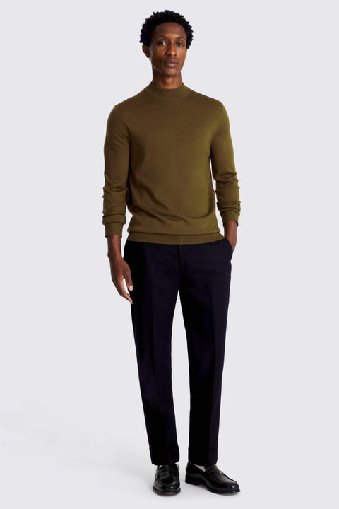 Man wearing a green sweater and black pants on a white background