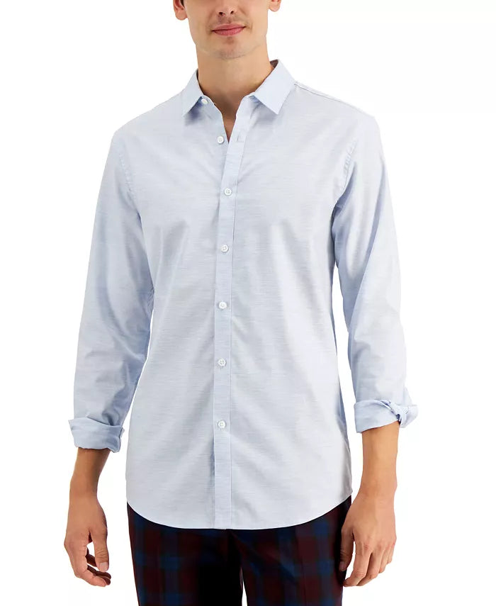Man wearing a light blue button-up shirt with rolled-up sleeves on a white background