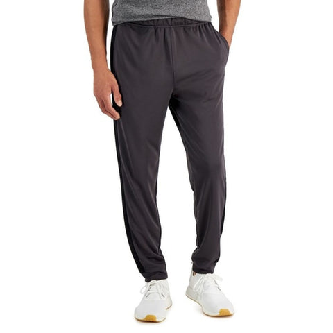Person wearing dark gray jogger pants and white sneakers on a white background