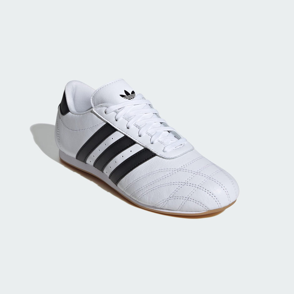 White Adidas sneaker with black stripes on a light gray background