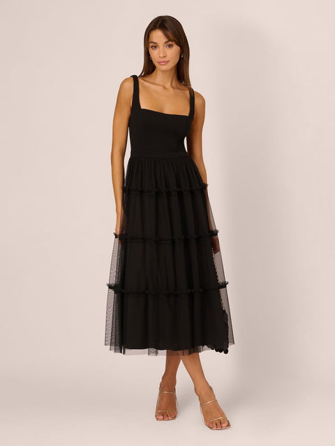 Woman wearing a black tiered dress on a plain background