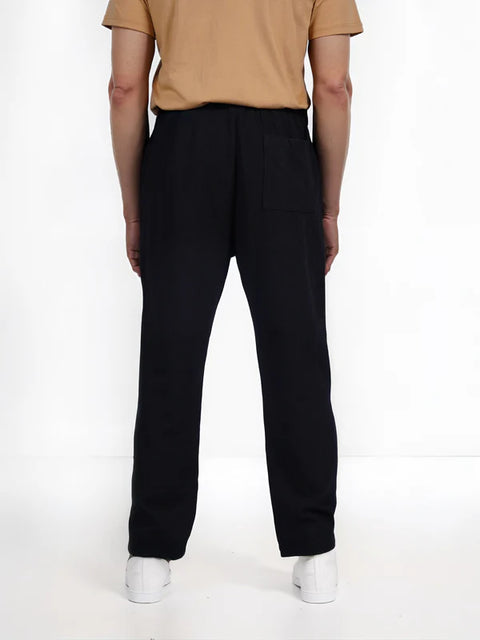 Person wearing black pants and a beige shirt on a white background