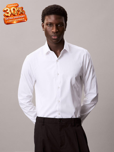 Man wearing a white dress shirt and black pants against a plain background