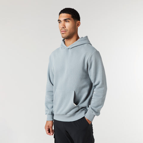 Man wearing a light blue hoodie on a plain background