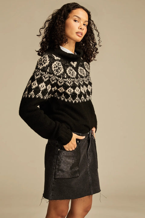 Woman wearing a black and white patterned sweater with a plain background