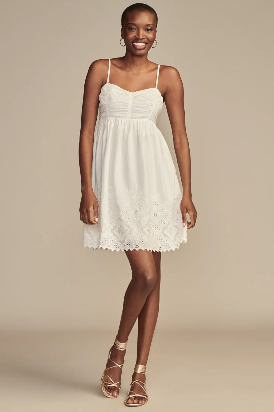 Woman wearing a white lace dress against a beige background