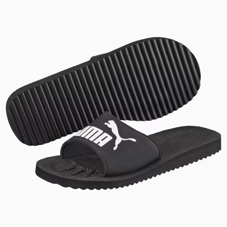 Black Puma slide sandals with a white logo, showing both the top strap design and the textured sole.