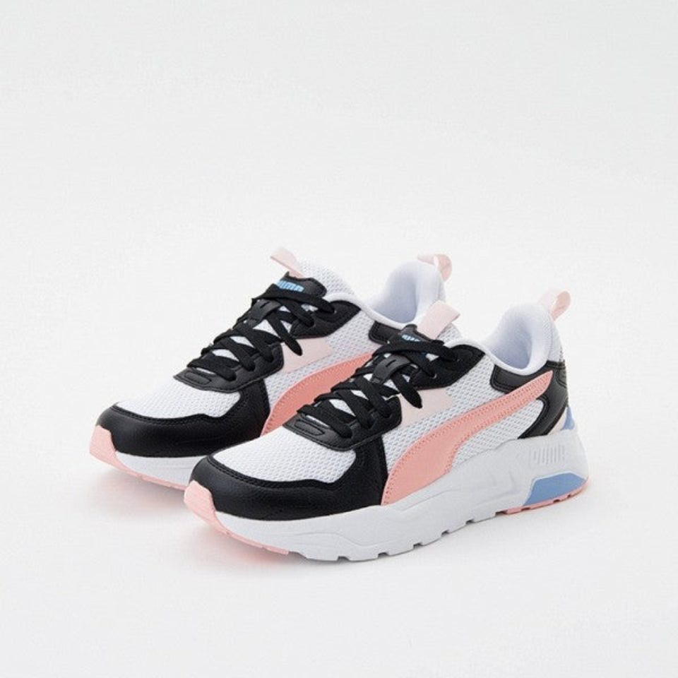 A pair of Puma sneakers in white, black, and pink, featuring the iconic Formstrip design and a light blue accent on the sole, set against a plain light gray background.