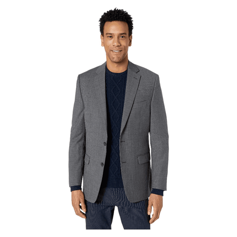 Man wearing a gray blazer over a navy sweater and pants on a white background