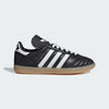Black Adidas sneaker with white stripes on a light gray background