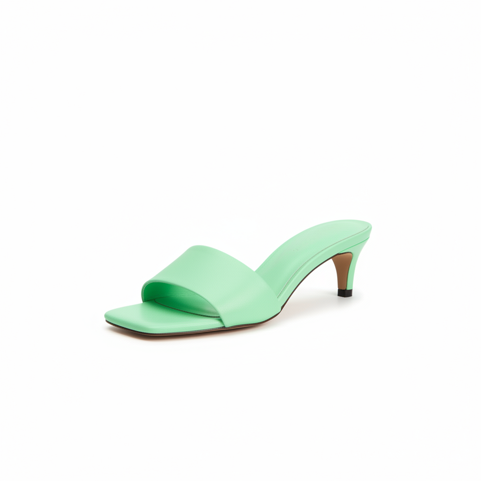 Green high-heeled sandals worn by a person on a white background