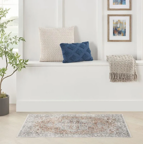 Living room with textured pillows, blanket, and rug on a white wall background