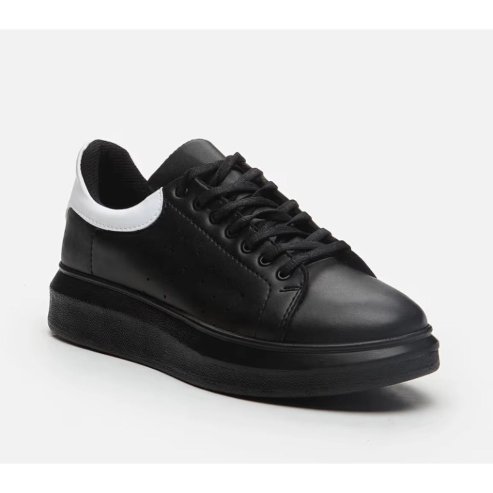 A black leather low-top sneaker with a thick black platform sole, black laces, and a contrasting white side accent, shown on a light gray background.