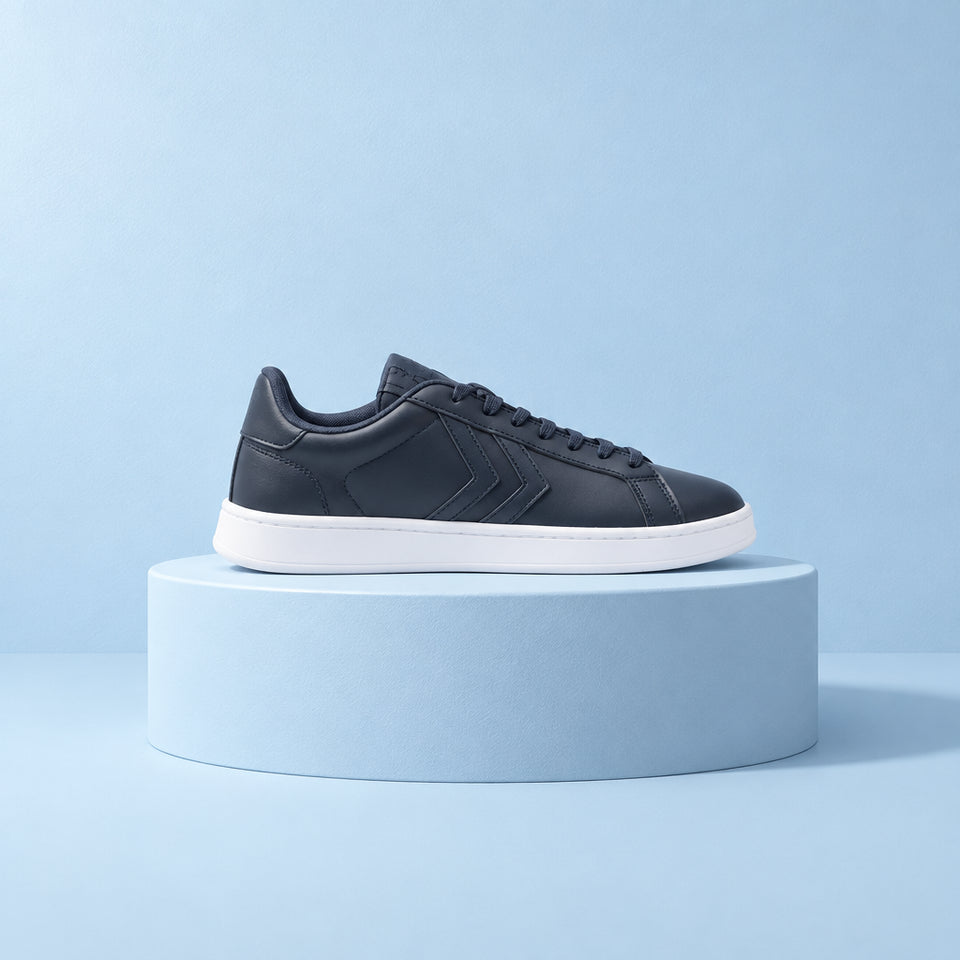 A single low-top sneaker shown in profile against a plain white background. The shoe features a dark gray leather upper with tonal chevron stripes, matching gray laces, and a thick white rubber sole.