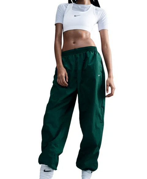 Person wearing a white Nike crop top and green Nike pants on a white background